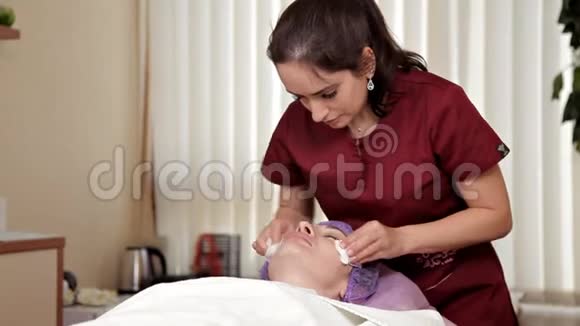 美容师在湿巾的帮助下从面具的残留物中清洁一个漂亮女孩的脸化妆品视频的预览图