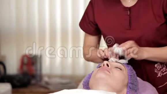 美容师在湿巾的帮助下从面具的残留物中清洁一个漂亮女孩的脸化妆品视频的预览图