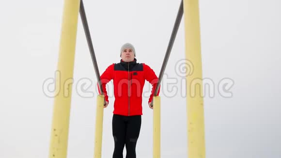 一个受过体育训练的人在冬天在露天的双杠上做俯卧撑总体计划的基本观点视频的预览图