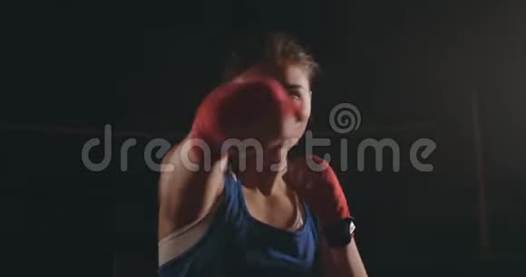 一个漂亮的女拳击手直接对着镜头看着镜头在黑暗中向前走视频的预览图
