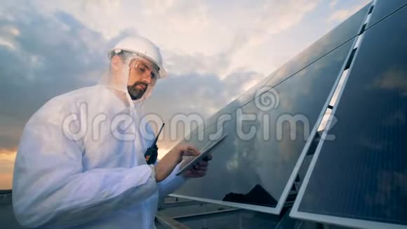 能源工人站在太阳能装置旁操作平板电脑视频的预览图