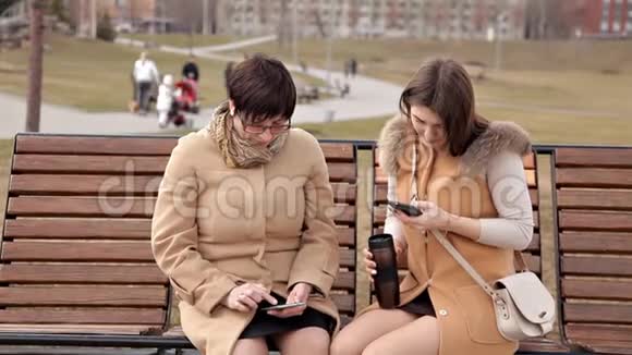 母女俩坐在公园里交流用手机性质关系视频的预览图