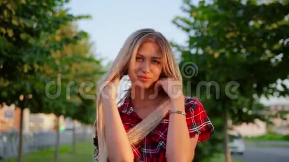 画像快乐可爱的金发女孩穿着格子红衬衫拉直了长长的秀发和笑容视频的预览图