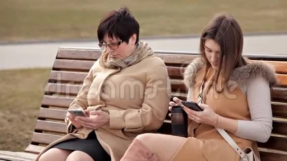 母女俩坐在公园里交流用手机性质关系视频的预览图