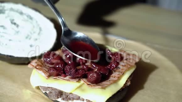 厨师的双手用烟熏培根和樱桃酱做一个美味的汉堡视频的预览图