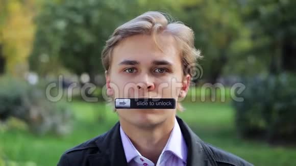 年轻可爱的男人的脸盯着相机嘴上贴着铭牌视频的预览图