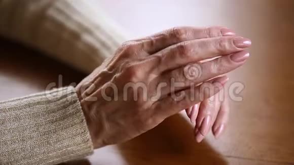 老雌性皱皱的双手叠在桌子上近距离观看视频的预览图