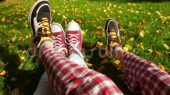 公园里的约会一男一女坐在阳光下的草地上我们只看到他们的鞋子视频的预览图