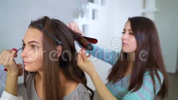 美容美发专家为年轻的黑发女人做专业的化妆和发型视频的预览图