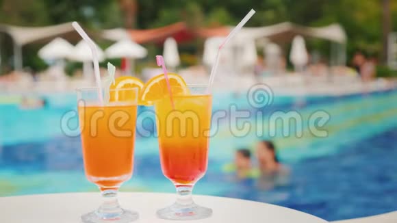 在旅游胜地游泳池的背景下提供两杯异国风味的鸡尾酒视频的预览图
