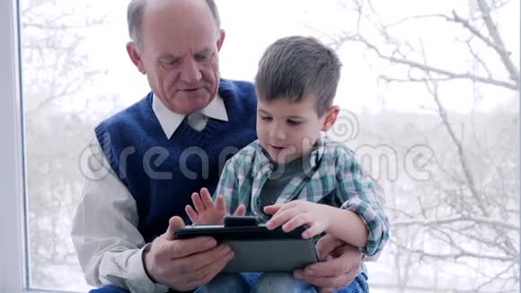 爷爷和孙子在室内玩电脑游戏视频的预览图