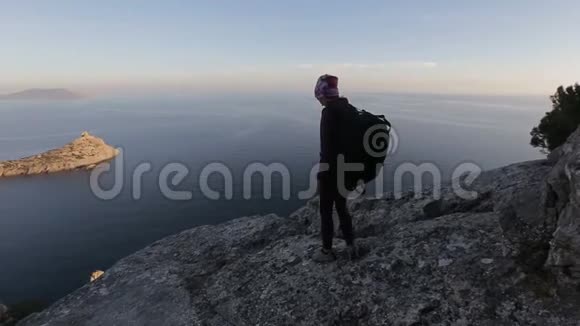 一个年轻女子在海的高处行走的特写镜头女士在山顶上美丽的风景面对大海视频的预览图