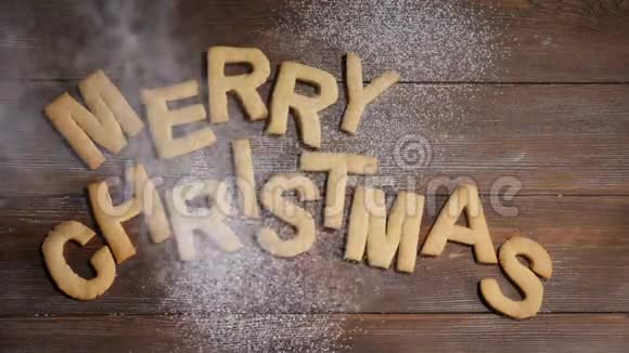 新年快乐圣诞快乐纸条上面写着棕色木制背景的饼干字母白色粉末视频的预览图