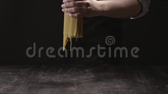 厨师手把生的意大利面食扔在黑色背景的木制乡村餐桌上慢动作全高清视频视频的预览图