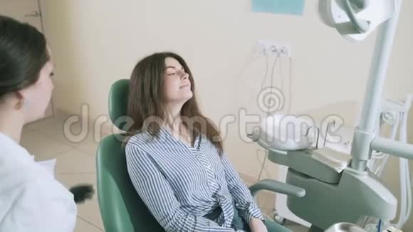 一位美丽的浅黑色的长发穿着时尚的衣服来到牙医办公室治疗她的牙齿慢慢地视频的预览图