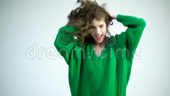 一个穿着绿色毛衣的卷曲女孩飘扬着她的头发穿冬装的巴黎女孩时尚外观和美容理念视频的预览图