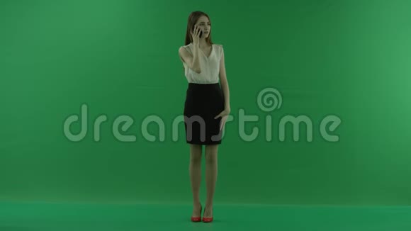 一位身穿白衬衫黑裙的年轻商务女性正站在前面的手机上交谈视频的预览图