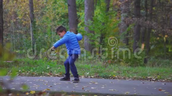 小男孩在秋天公园户外玩玩具陀螺视频的预览图