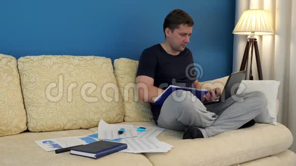 男人坐在沙发上用笔记本电脑和财务图表工作小生意视频的预览图