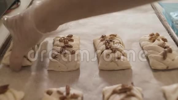 合上糖果手把未煮熟的面包和坚果放在烤箱托盘上库存录像面包师准备甜点视频的预览图