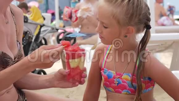 快乐的小女孩在海滩上吃西瓜片暑假户外野餐视频的预览图
