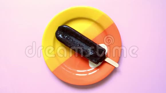 传统巧克力冰淇淋在夏天融化在一个美丽的明亮橙色盘子上柔软的粉红色背景视频的预览图