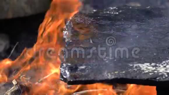 野餐篝火脂肪沸腾的油流出来在明亮的篝火上滴在热石上准备露营视频的预览图