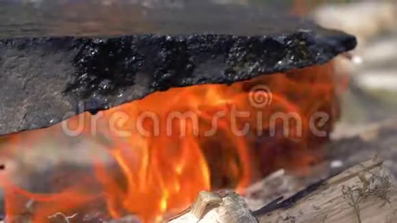 野营时脂肪沸腾的油流出来在野餐时在明亮的篝火上滴在热石上视频的预览图