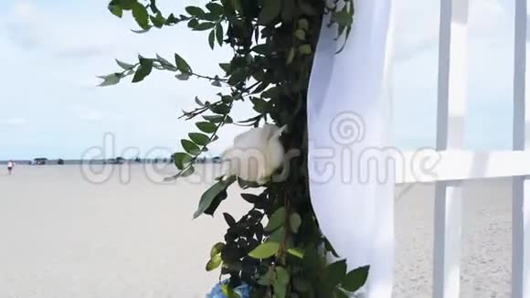 在海滩上举行婚礼在海滩上举行婚礼的流产用花装饰的婚礼拱门拱门视频的预览图