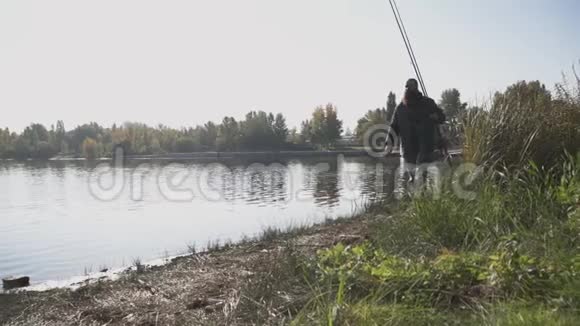孤独的长胡子渔夫拿着钓竿走在河岸上那人向远处望去掩护视频的预览图