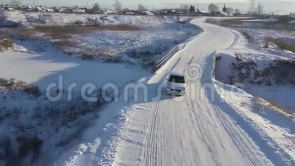 白色的汽车在冬天的田野里穿过覆盖着雪的桥桥下有一条狭窄的冰冻河流库存数据视频的预览图