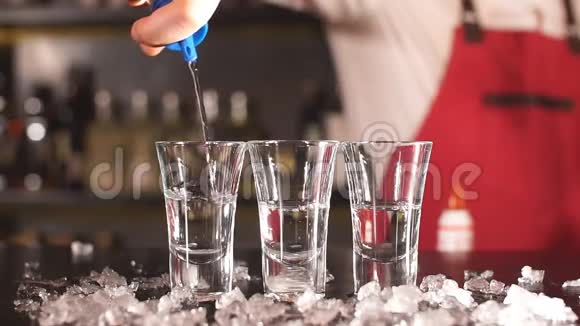 特写调酒师把一些饮料从瓶子里倒入木制柜台上的镜头玻璃视频的预览图