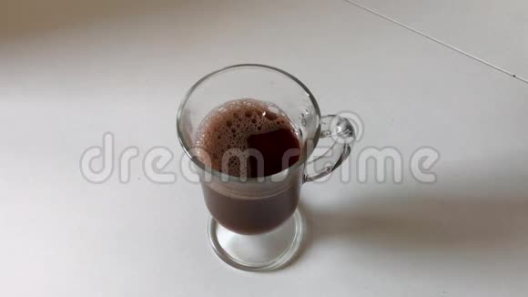 慢动作将可可饮料装在玻璃罐中并用手柄放在白色桌子上视频的预览图