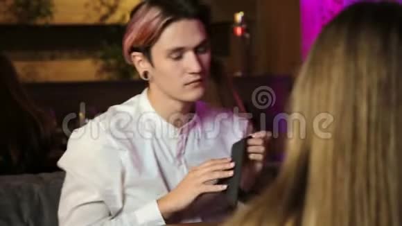 年轻人坐在咖啡馆里和一个女人说话用餐巾擦嘴唇视频的预览图