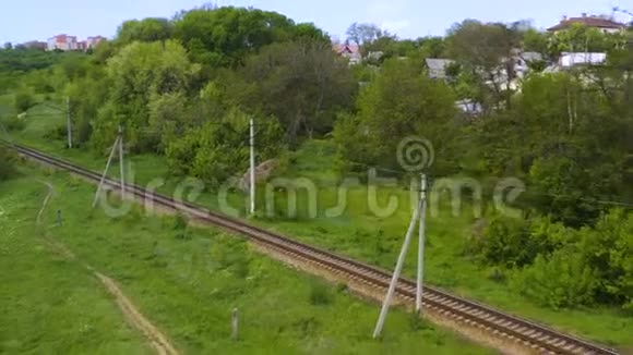 在穿越森林丘陵的铁路上行驶的单独的火车机车上的鸟瞰图视频的预览图