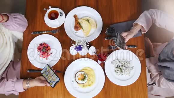 两个穆斯林妇女坐在餐馆里有食物的盘子视频的预览图