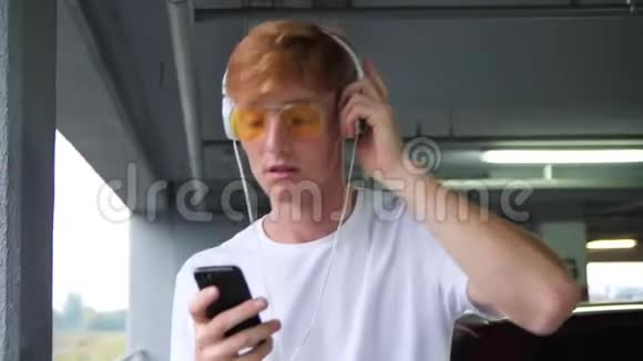 时尚的红发男人用耳机听电话音乐视频的预览图