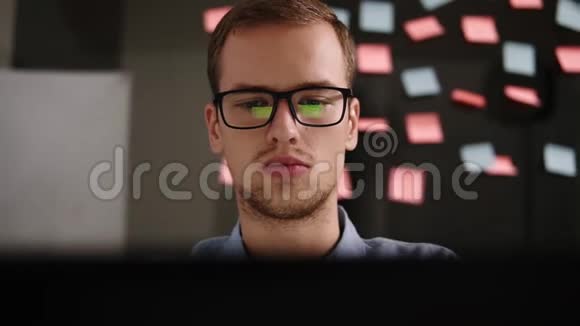 戴眼镜的年轻人在办公室的笔记本电脑上工作商人上班族男学生在视频的预览图