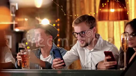 朋友男人女人休闲友谊和技术概念在酒吧或酒吧喝啤酒的智能手机朋友视频的预览图
