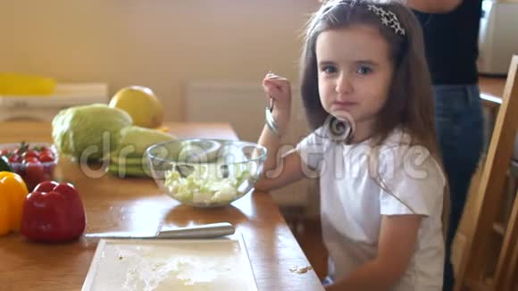 小女孩和妈妈准备沙拉把它装满植物油素食家庭健康食品视频的预览图