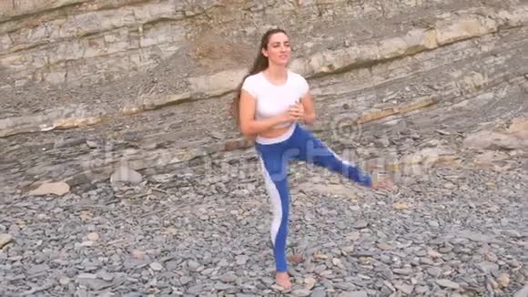 女孩正在做运动在岩石背景上的呼吸练习中腿抬起身体弯曲视频的预览图