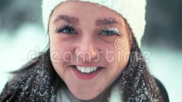 一个戴着白帽子的年轻女孩在雪地森林里散步视频的预览图
