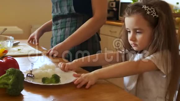 厨房里的长发女孩用食物推着他的盘子学龄前儿童的适当营养视频的预览图