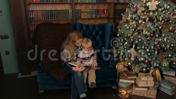 母亲和儿子在圣诞树附近看书视频的预览图