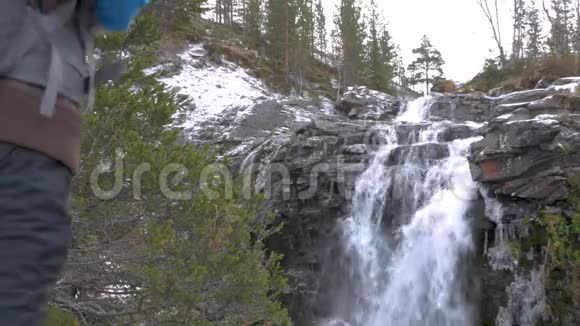 旅行者带着背包来到一个美丽的山瀑布健康的生活方式视频的预览图