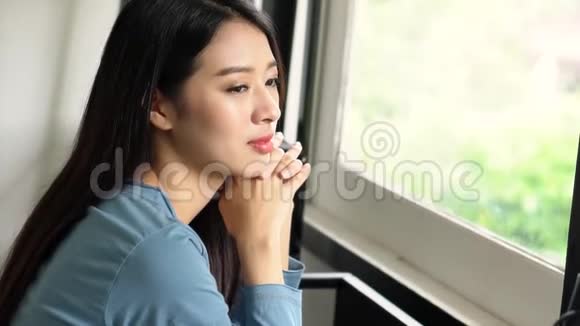 美丽的肖像年轻的亚洲女人坐在靠窗的椅子上微笑着在客厅里快乐着视频的预览图