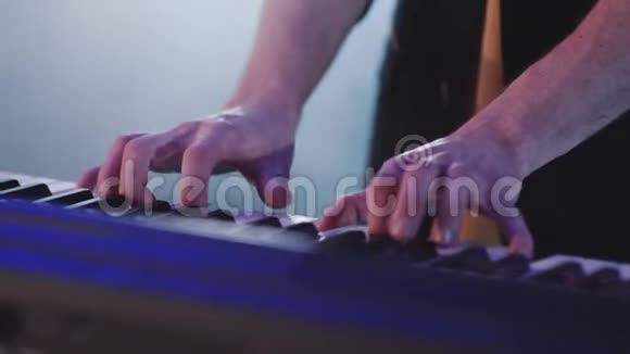 在五颜六色的舞台灯光下用手演奏电动钢琴视频的预览图