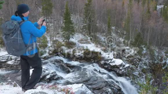 一个男人带着背包在一个美丽的山地公园里旅行下面是瀑布和河流的美丽景色他是视频的预览图