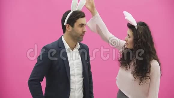 年轻情侣的粉色背景头上戴着黑黑的耳朵在此期间他们在视频的预览图