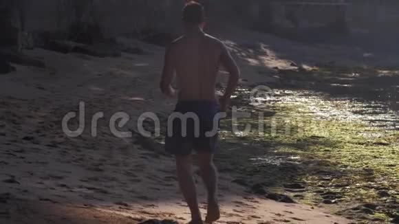 穿短裤的体操运动员沿着沙质海岸线奔跑视频的预览图